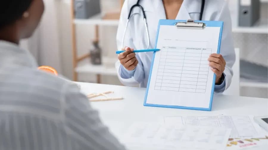A doctor is seen writing on a piece of paper.