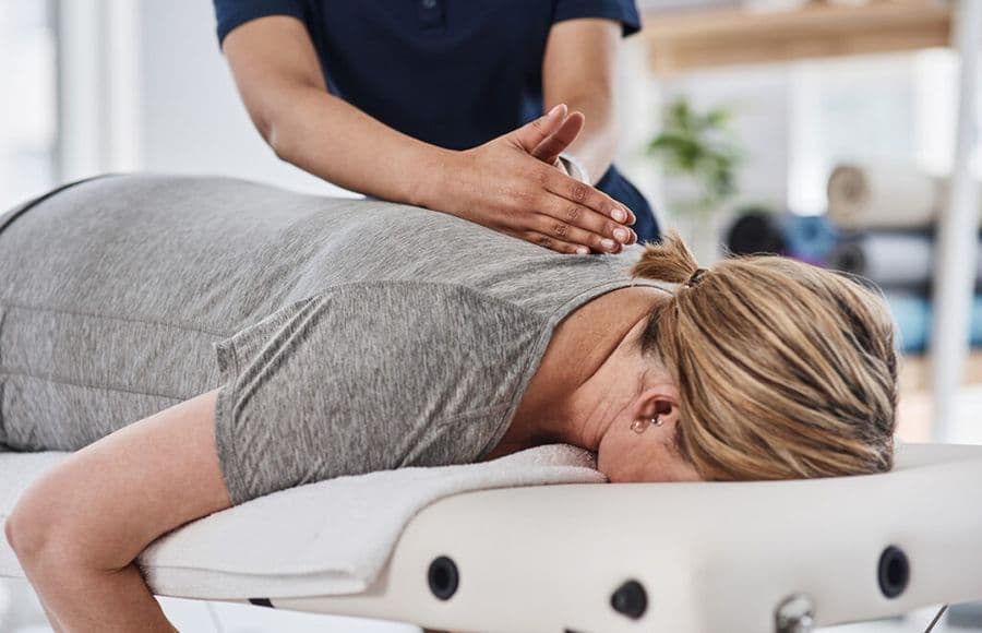 A woman is lying on a massage table, suggesting a scene focused on relaxation and comfort.