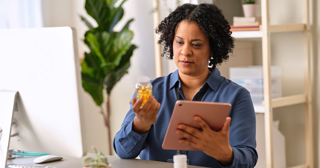 A person is indoors, holding a small object. The individual appears to be a woman, as indicated by the tags, and is wearing clothing.