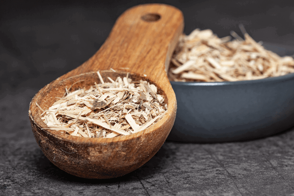 Siberian ginseng in dried plant form in wooden spoon and bowl
