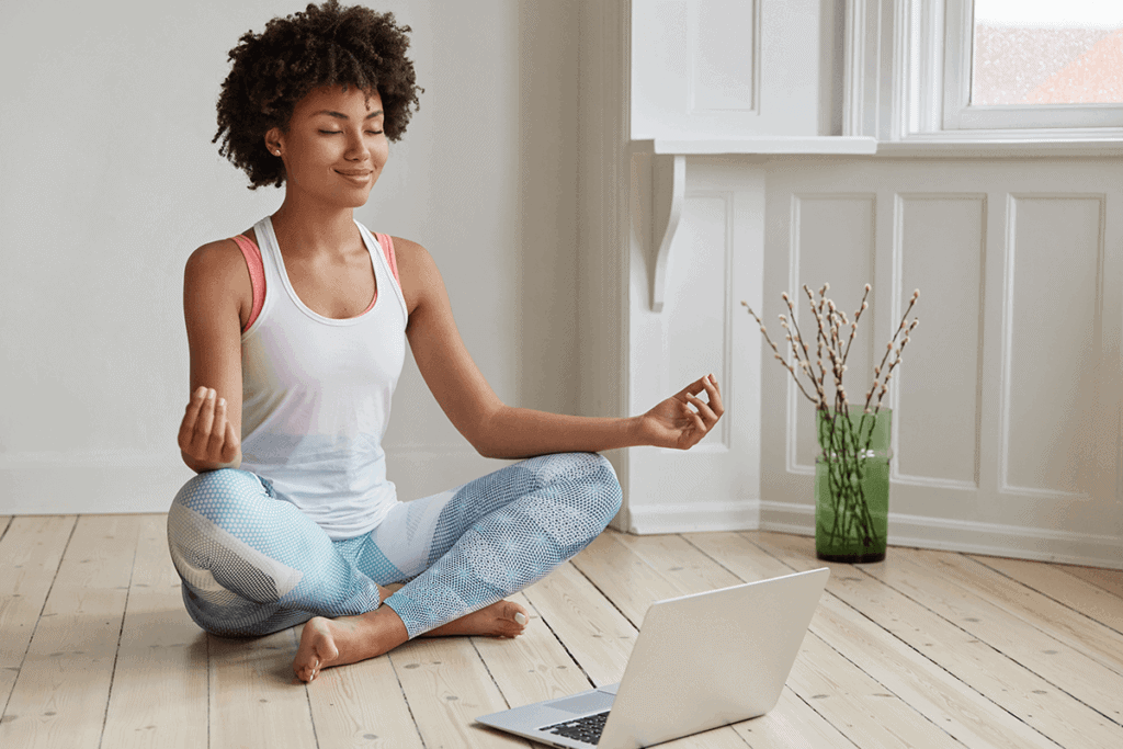 woman sitting on floor, meditation in front of open laptop