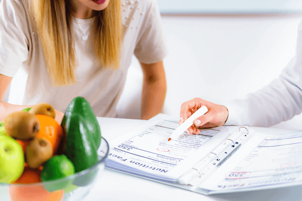 close up of nutrition chart with practitioner and patient leaning over looking at the chart and chatting