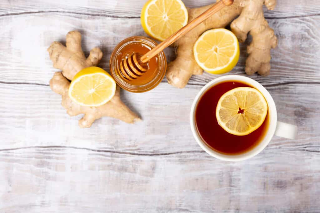 Cup of Ginger tea with lemon and honey on a dark blue background, top view