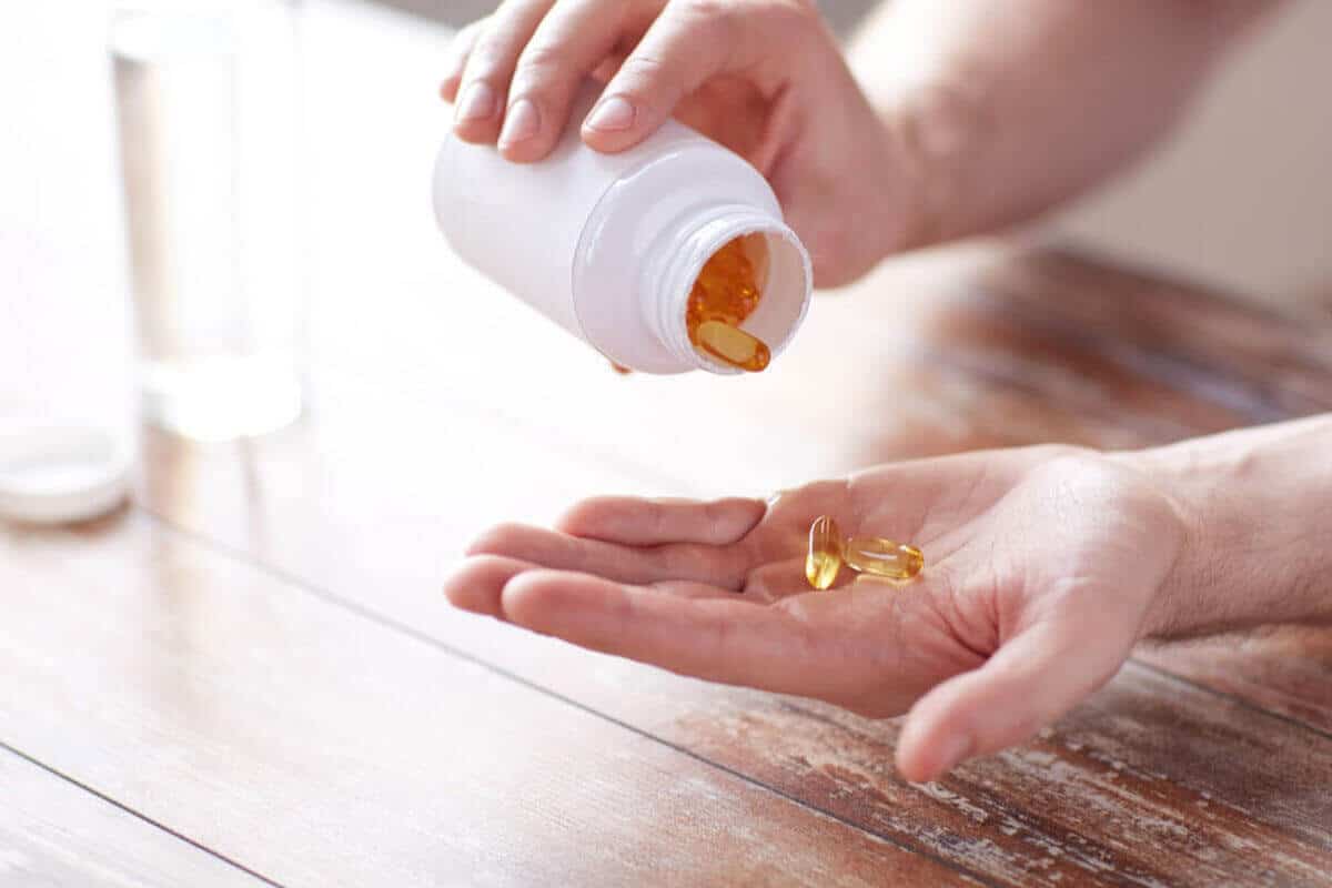 person getting fish oil from a supplement bottle