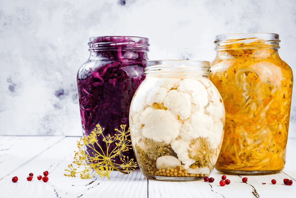 Jars of sauerkraut and pickled vegetables with herbs.