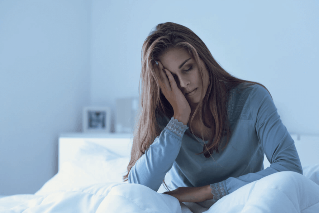 woman in bed holding her head