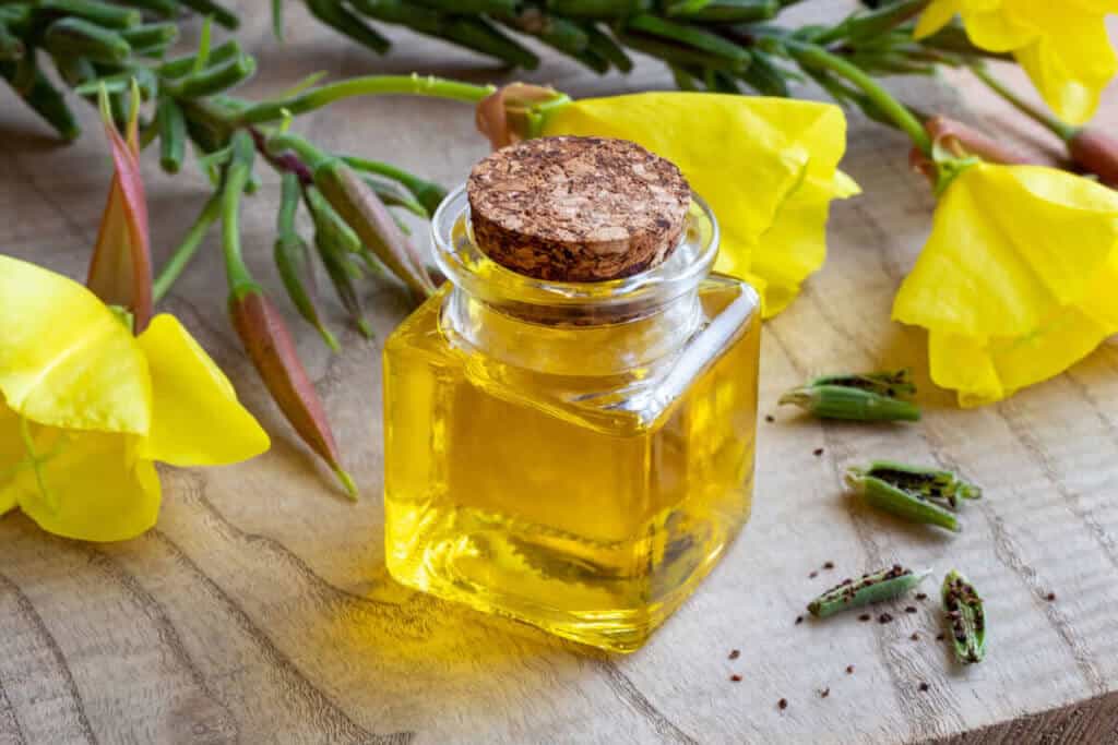 A bottle of evening primrose oil with flowers and seeds.