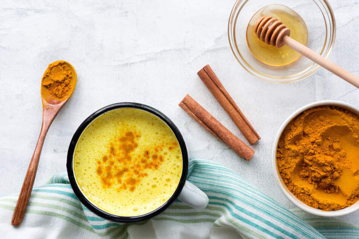 turmeric in a bowl, on a wooden spoon and in a latte