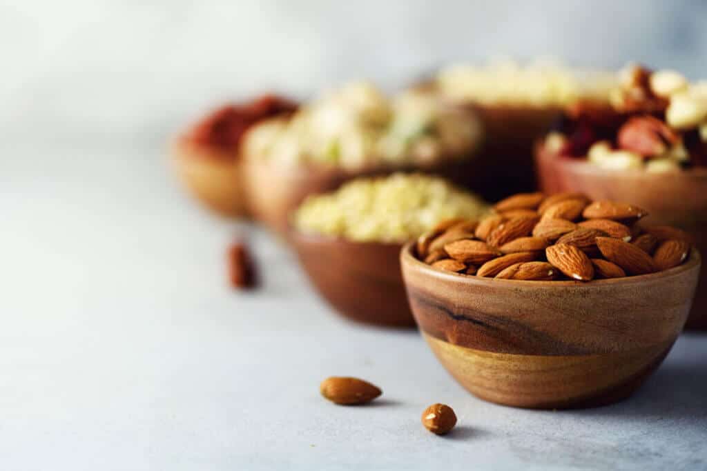 Almonds and mixed nuts in wooden bowls on a light counter