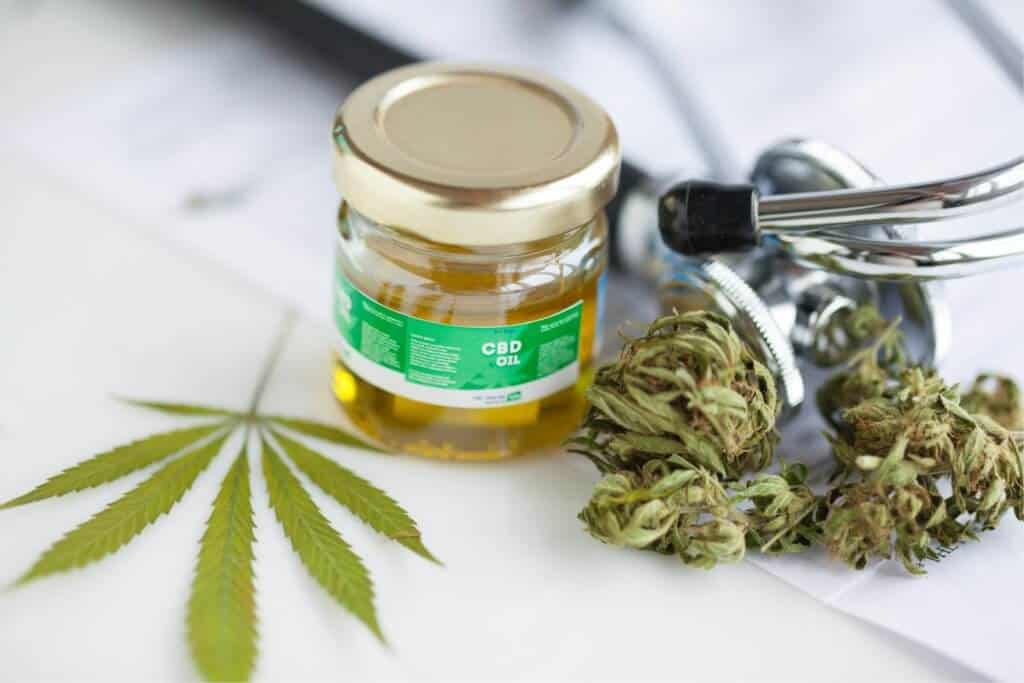 Jar of of CBD oil and a cannabis plant