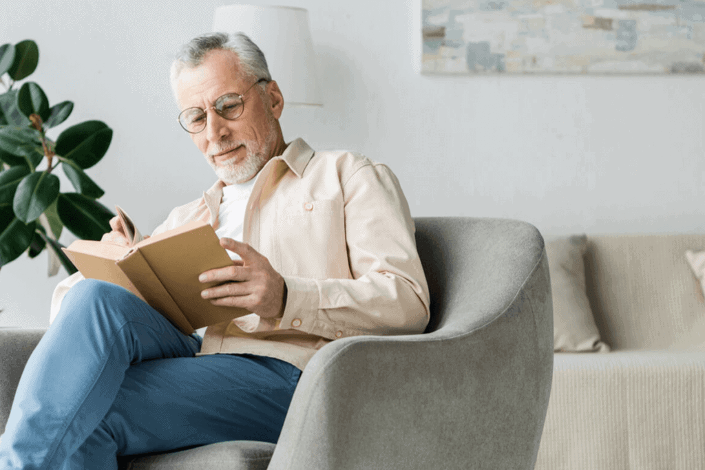 man sitting on couch in his living room reading a book
