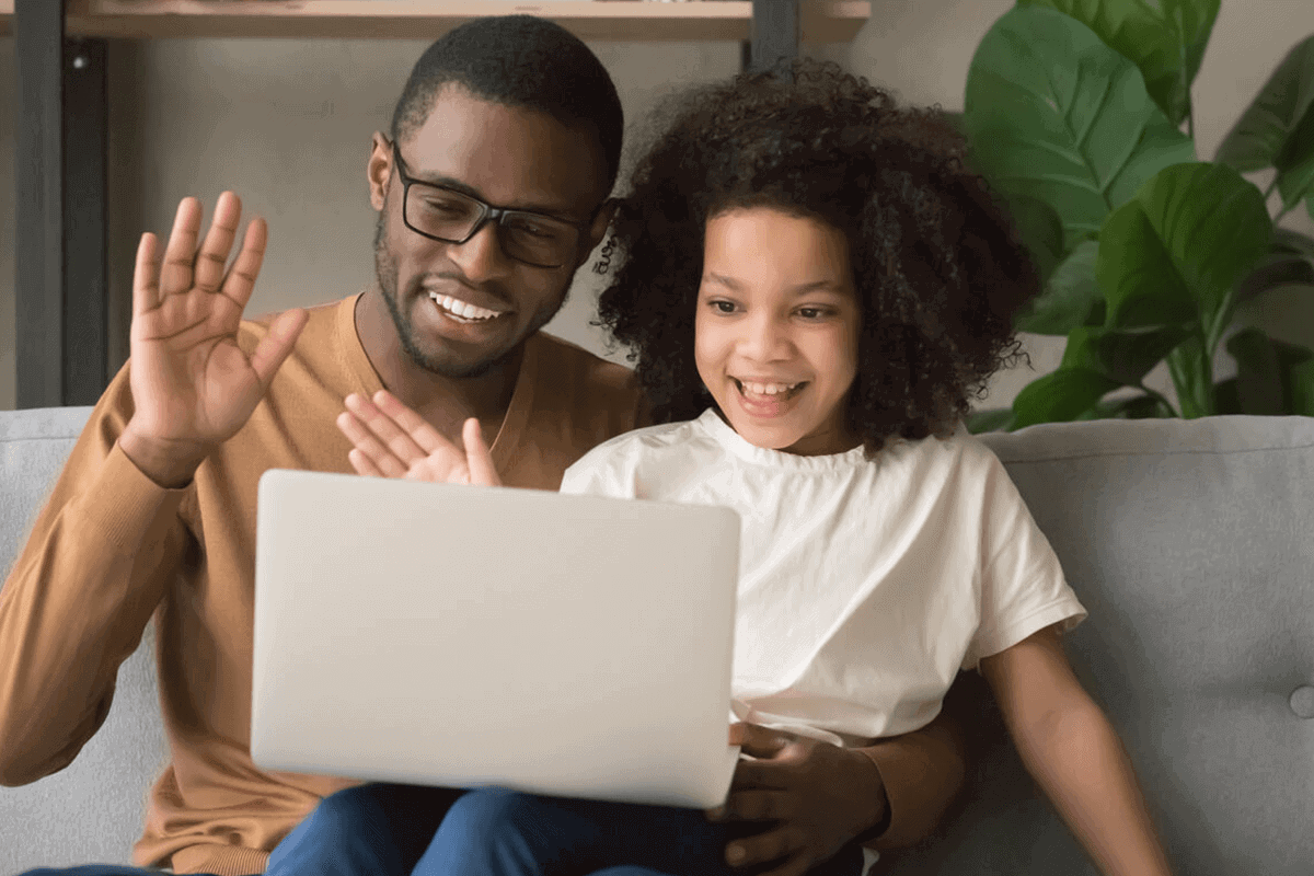 man and daughter waving at laptop