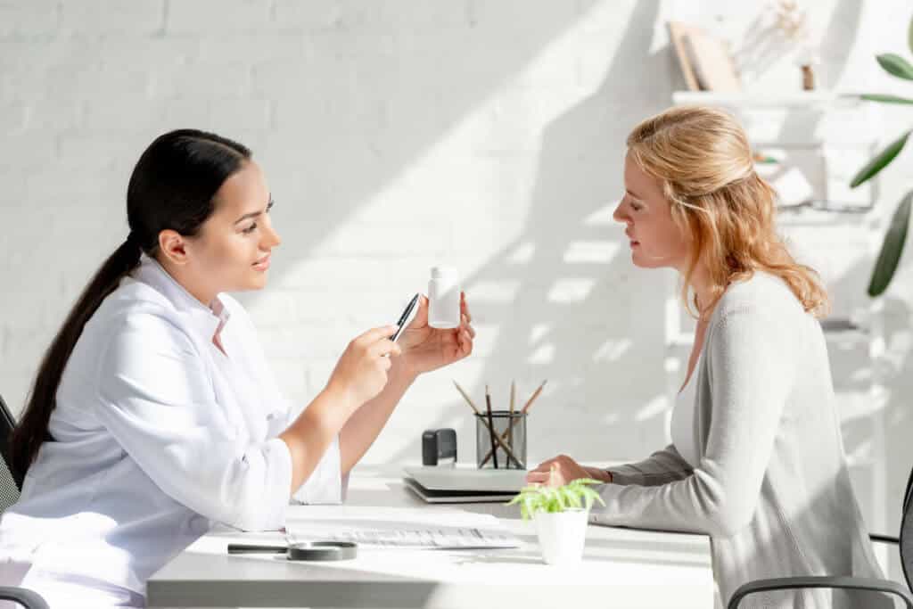 practitioner showing supplement bottle to patient