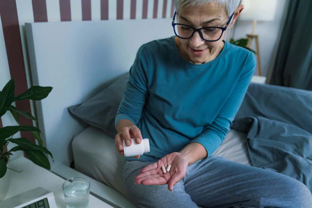 Person holding a pill and a glass of water