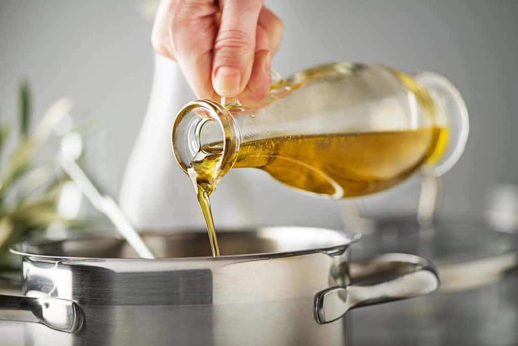 Person pouring cooking oil into a pot