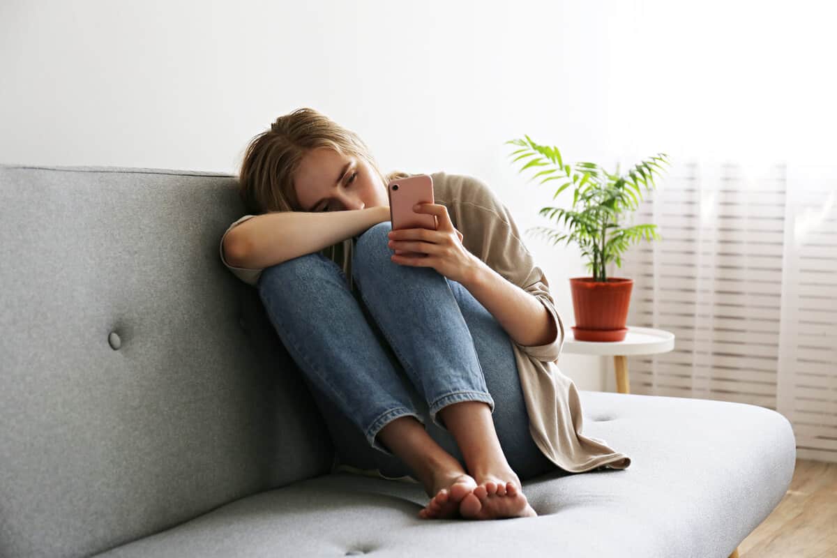 Woman sitting on a couch browsing on her phone.