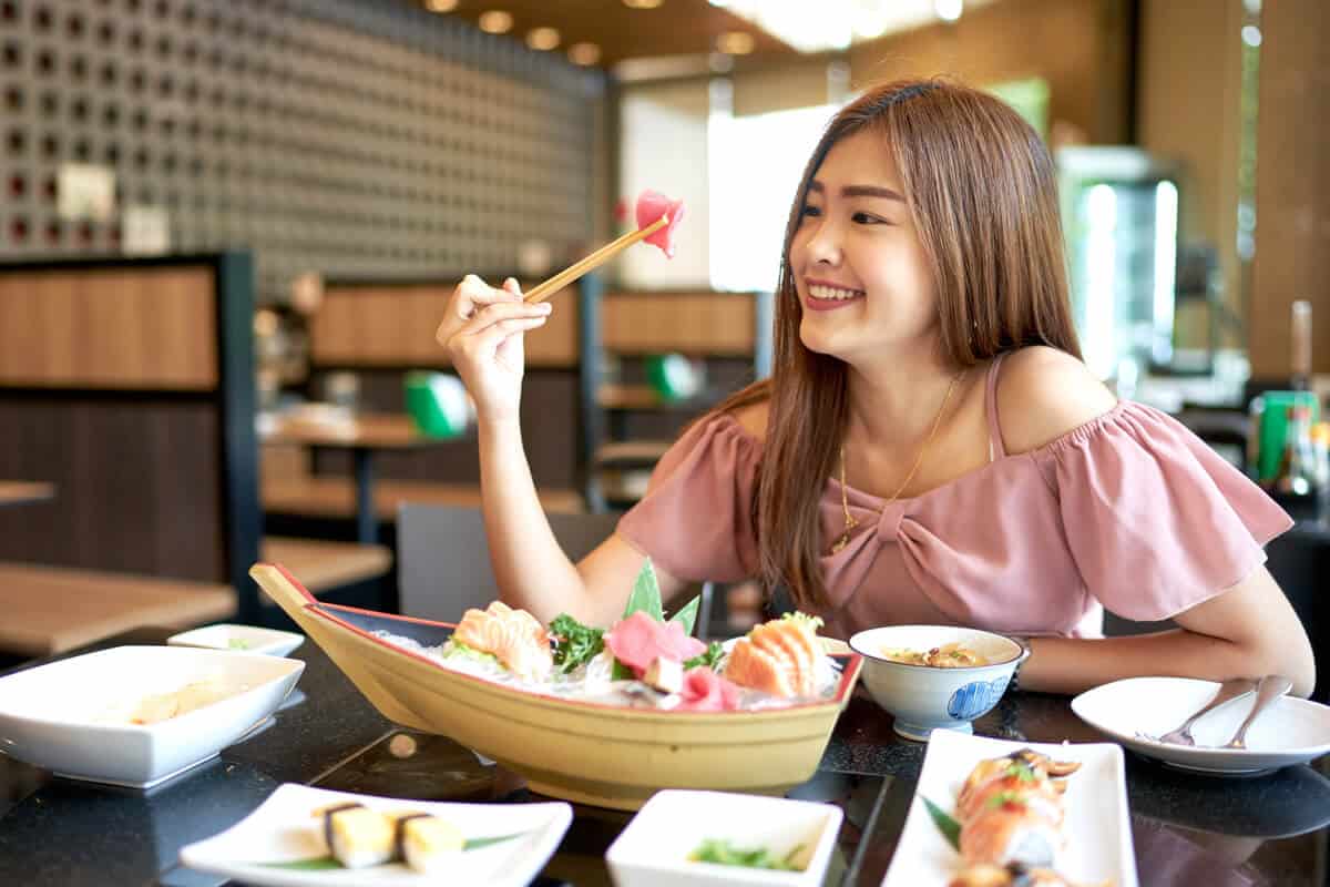 woman eating raw fish in a restaurant