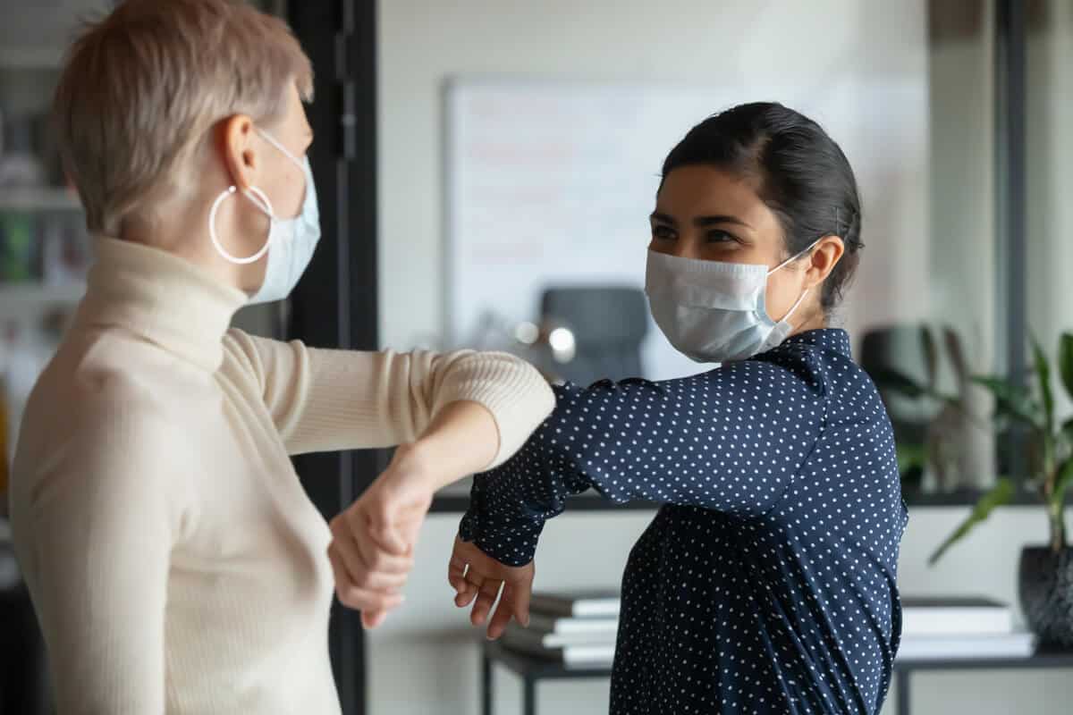 Two women bumping elbows 