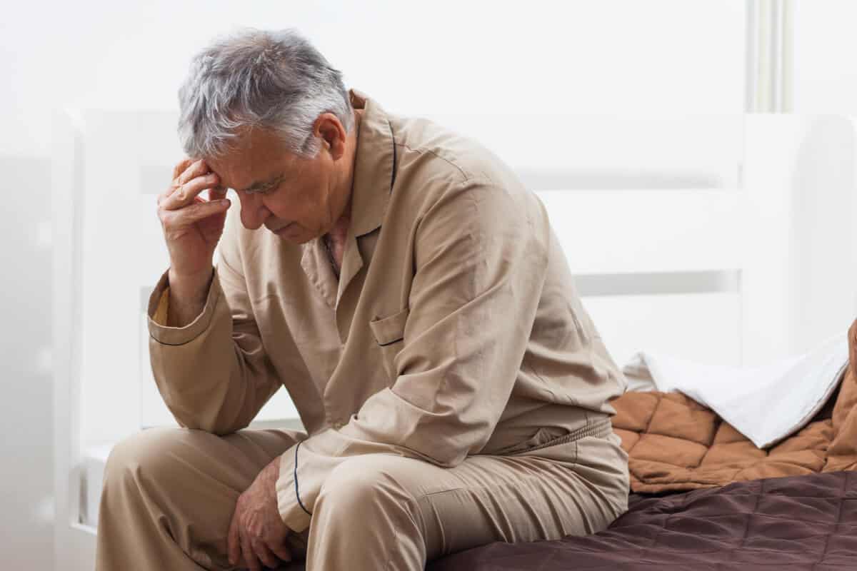 Man kneeling over holding head