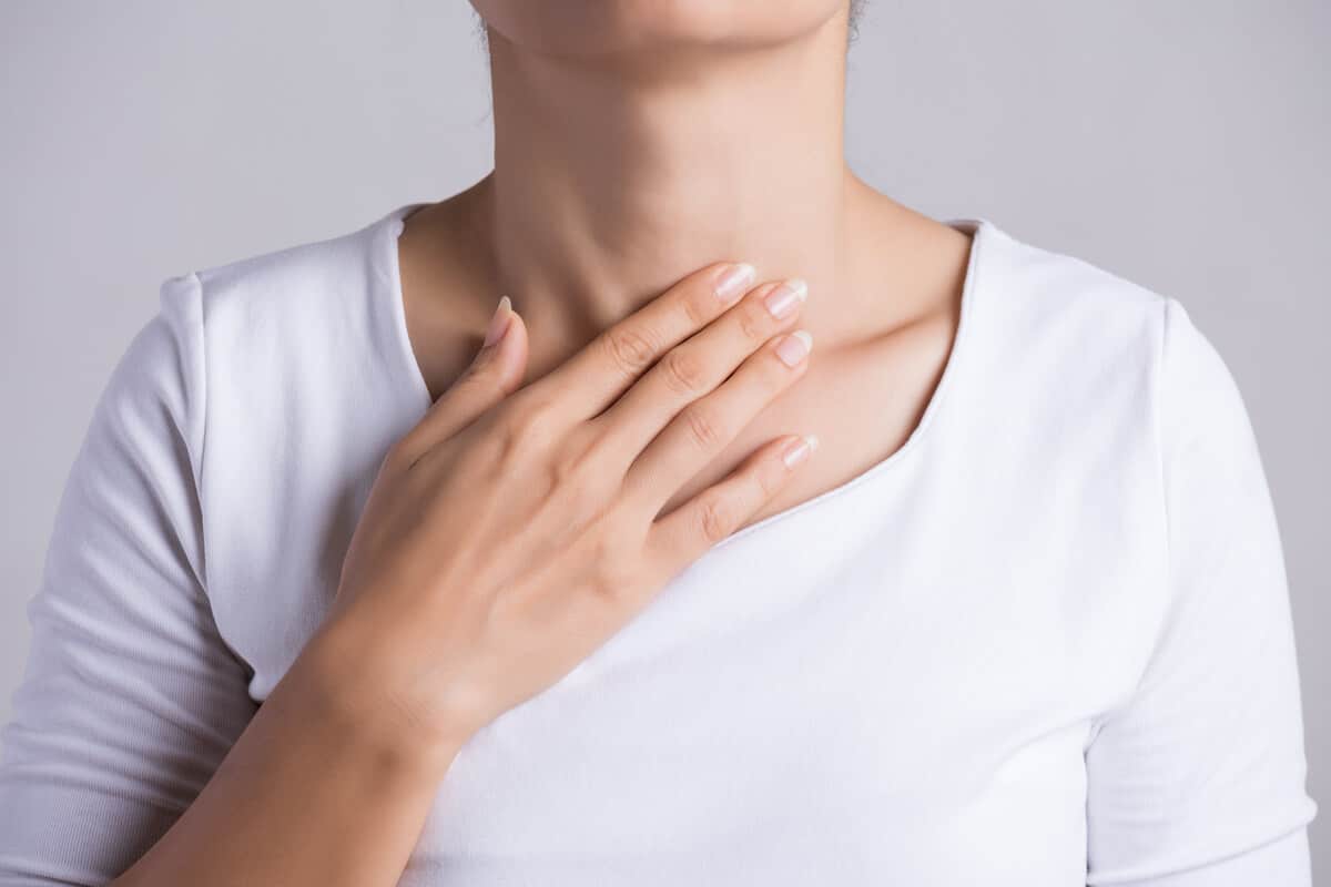 hypothyroidism vs. hyperthyroidism person holding throat