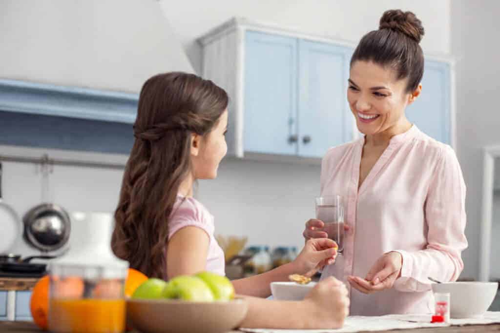 Woman giving a supplement to a child.