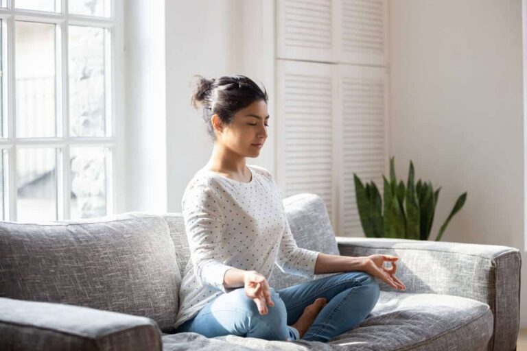 woman sitting on couch breathing and meditating