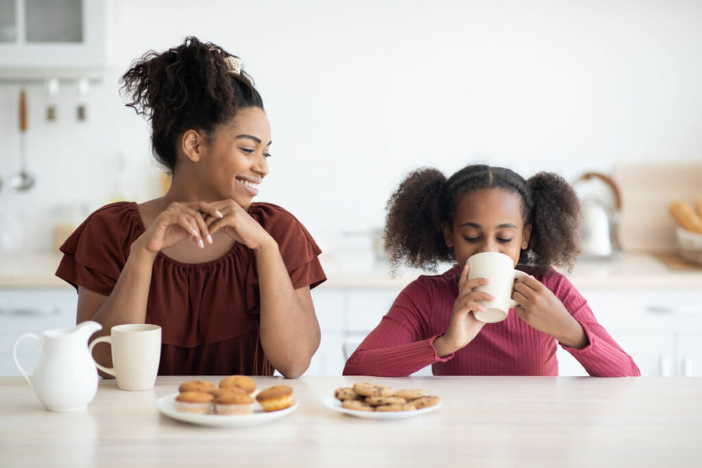 woman sitting at a table with a child drinking out of a cup