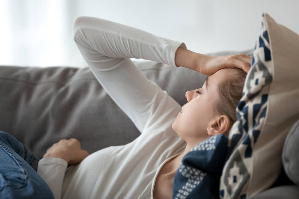 woman sitting on a couch holding her forehead