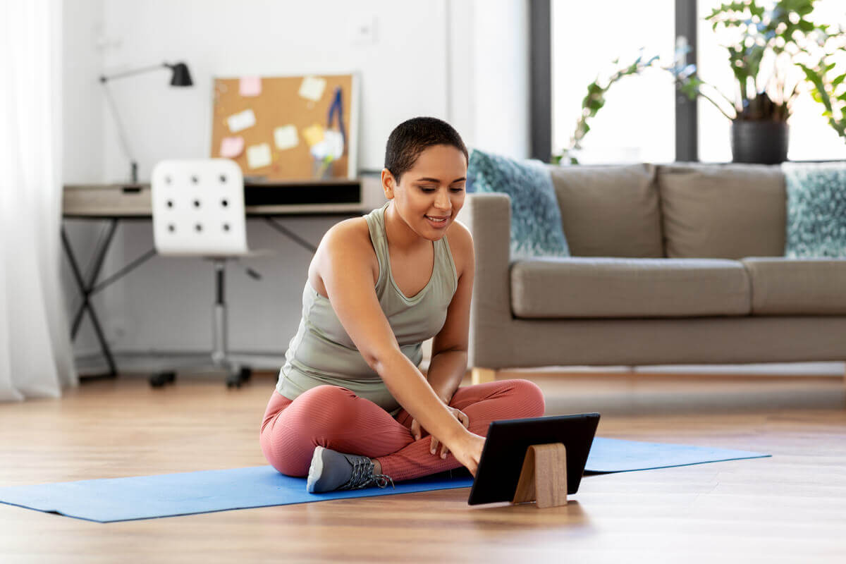 woman sitting on a yoga mat using a tablet