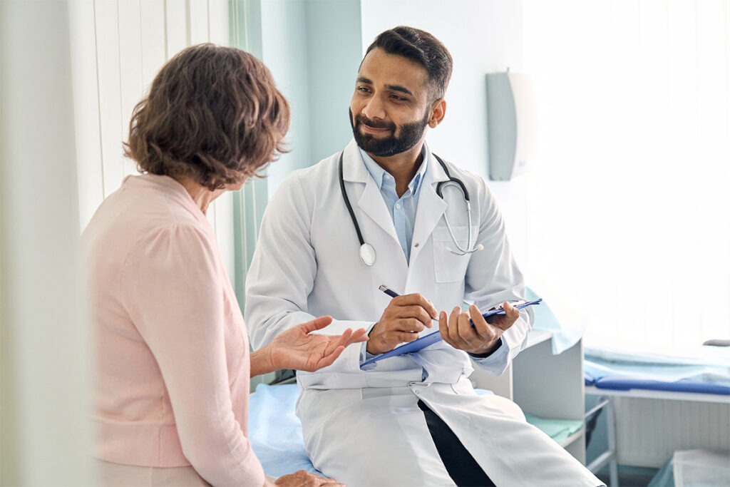 A man in a white coat is engaged in conversation with a woman.