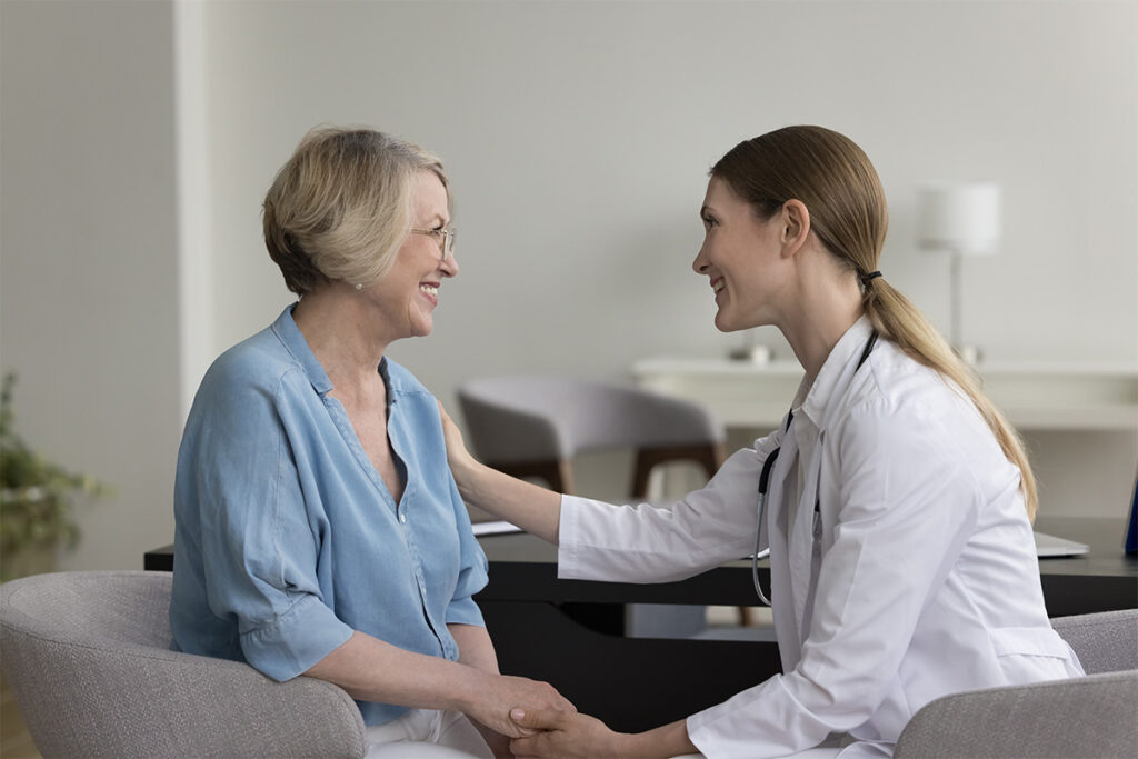 A woman is holding hands with a doctor in an indoor setting.